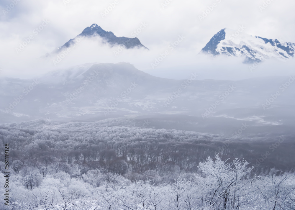 snowbound mountain valley in dense mist and clouds