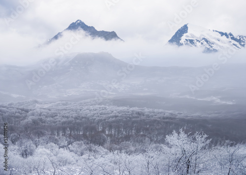 snowbound mountain valley in dense mist and clouds