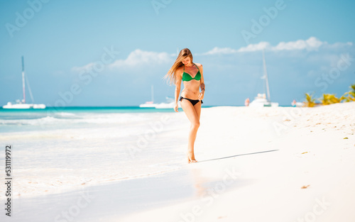 Young attractive blonde girl with perfect sport body in bikini on the tropical summer beach