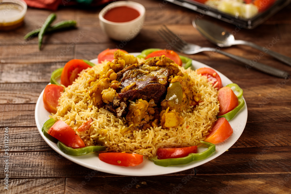 Madhbi beef or beef biryani with tomato sauce and salad served in a dish isolated on wooden table background side view of fastfood Madhbi beef or beef biryani with tomato sauce and salad served in a dish isolated on wooden table background side view of fastfood
