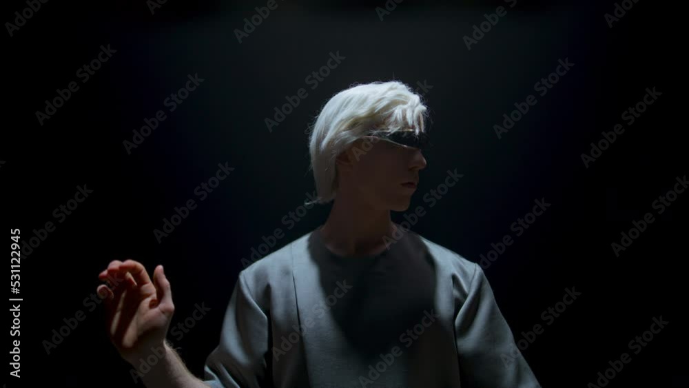Guy using vr headset in dark room. Focused player gesturing touching invisible Guy using vr headset in dark room. Focused player gesturing touching invisible