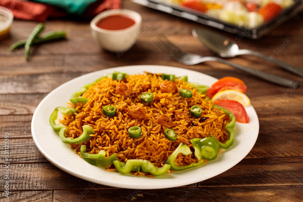 Machboos prawns or prawns biryani with tomato sauce and salad served in a dish isolated on wooden table background side view of fastfood Machboos prawns or prawns biryani with tomato sauce and salad served in a dish isolated on wooden table background side view of fastfood