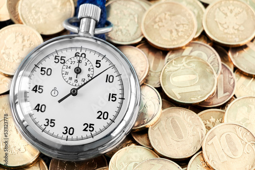 Analog stopwatch and pile of gold coins on a black background close-up. Counting time by stopwatch. Time measurement. Time management concept.A tool for measuring time.Dial stopwatch arrow