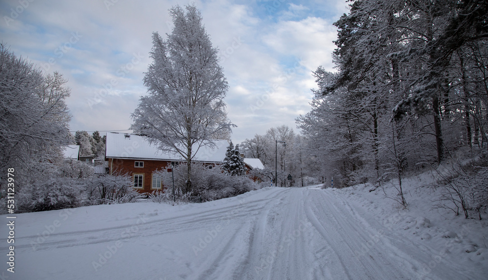 Snow covered road and red brick house in winter village