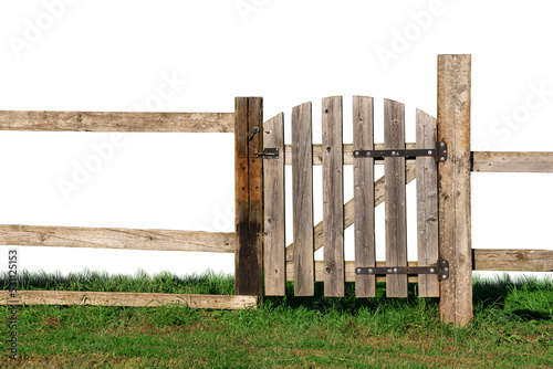 An old wooden fence with a closed gate on the green grass.