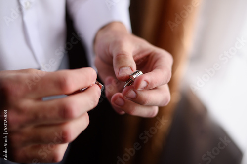 Portrait of a fashionable man holding stylish cufflinks in his hands. Wedding day concept, young modern businessman