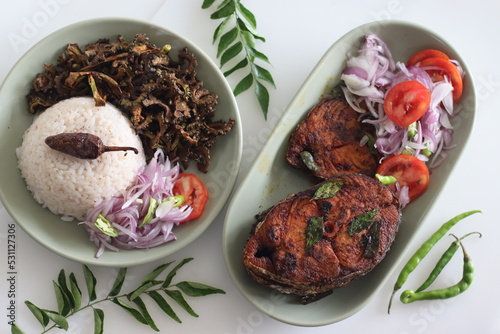 Crispy Surmai fish fry served with white rice meal along with fried bitter gourd and onion tomato salad called challas. Prepared by shallow frying king fish in Kerala style photo