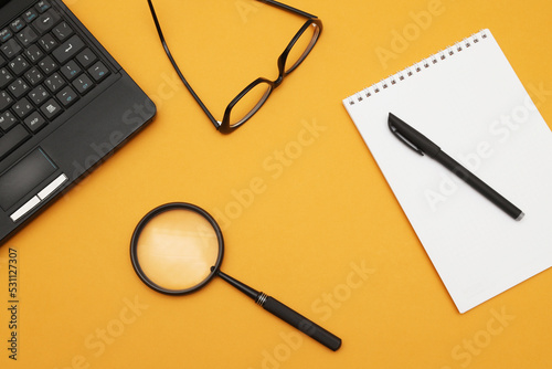 Loupe or magnifying glass on an orange background. Shallow depth of field