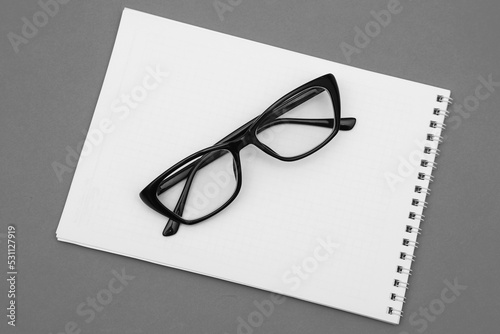 Spectacles with diopters in a black frame on white paper. Shallow depth of field