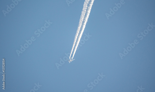 Passenger plane with a white trace of steam on a background of a blue sky without clouds. Air Transport.