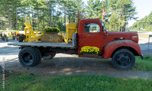 Old red flatbed truck decorated with flowers and chairs
