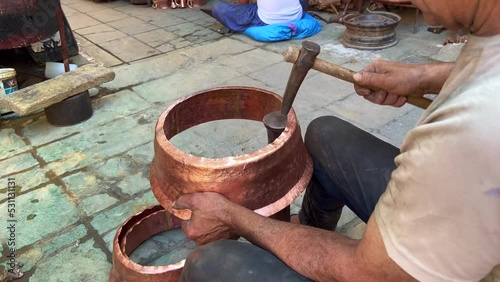Man manually processing metal pots in the old Medina of Fes