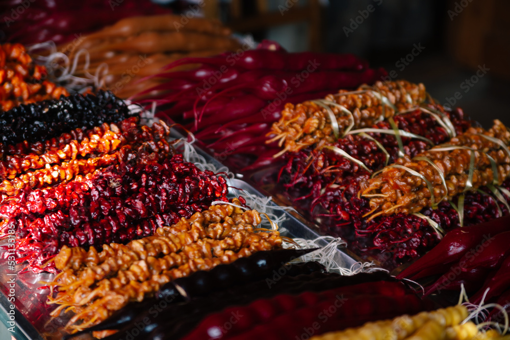 Caramelized walnut, nuts on a string, different colors are sold at a market place in Georgia. Near churchkhela, red grape, pomegranate and orange flavor
