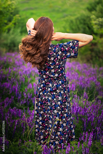 A girl in a purple dress on a background of blue flowers