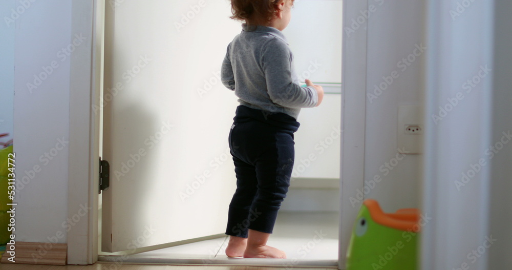 Baby standing by home bathroom, one year toddler stands observing Baby standing by home bathroom, one year toddler stands observing