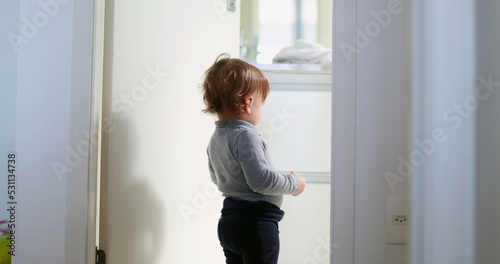 Baby standing by home bathroom, one year toddler stands observing