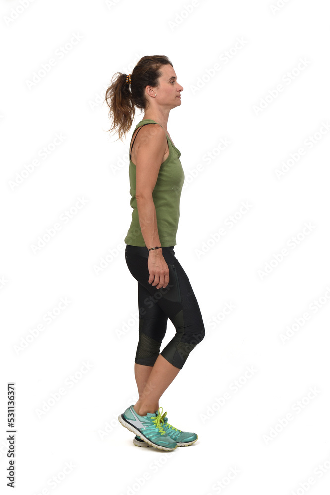 side view of a serious woman with sportswear walking on white background,