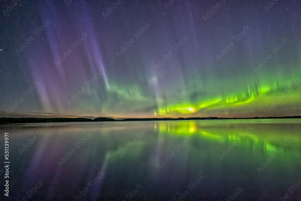 Northern lights dancing over calm lake in norrth of sweden.