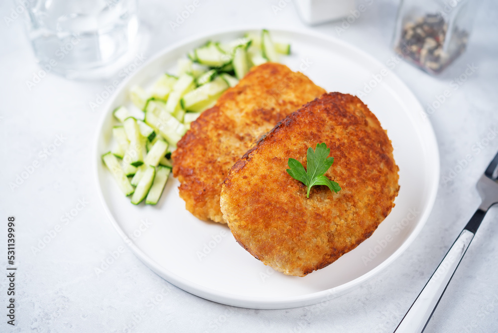 Fresh prepared schnitzel in a plate with fresh cucumber slices Fresh prepared schnitzel in a plate with fresh cucumber slices