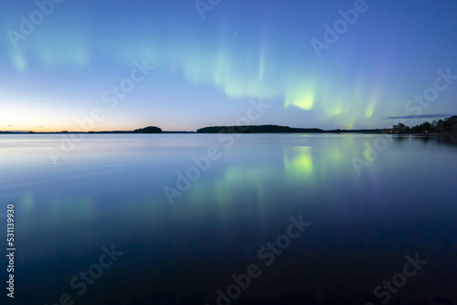 Northern lights dancing over calm lake in norrth of sweden. photo