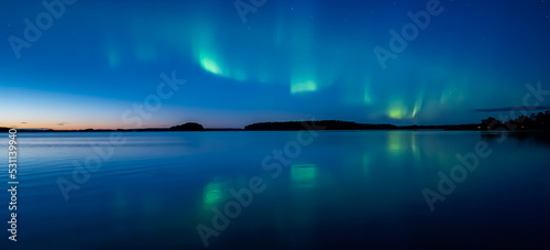 Northern lights dancing over calm lake in norrth of sweden. photo