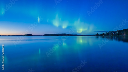Northern lights dancing over calm lake in norrth of sweden.
