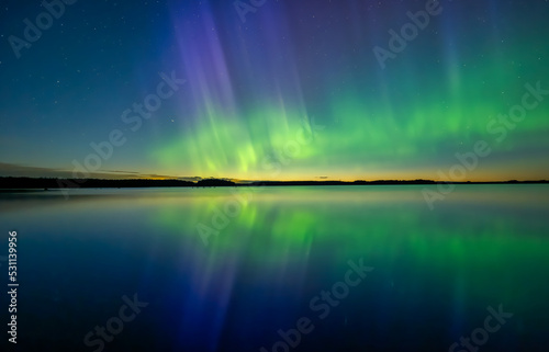 Northern lights dancing over calm lake in norrth of sweden.