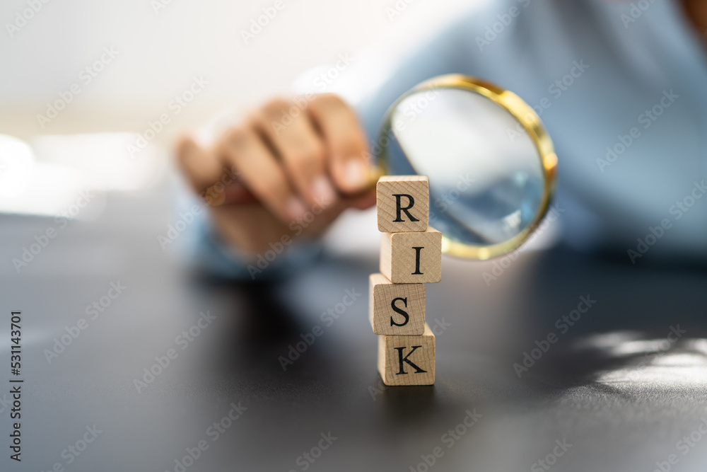 Fototapeta premium Hand Looking At Risk Blocks Through Magnifying Glass