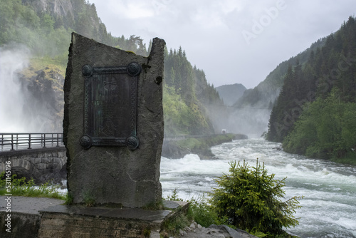 Skare, Norway - June 12, 2022: Wonderful landscapes in Norway. Vestland. Beautiful scenery of Latefossen waterfall under the Lotevatnet lake on the Hardanger scenic route. Cloudy day. Selective focus photo