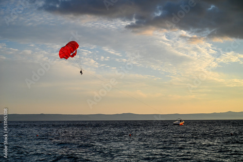 Parasailing on the sea. towed parachute against blue sky. Parachute and boat on the sea at summer. Tourist having fun with parachute on the sky. Extreme sport and adventure. 