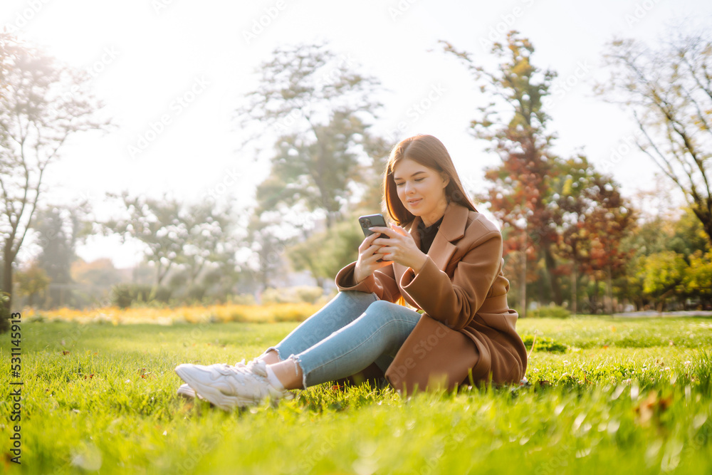 Pretty woman with smartphone having a good time in autumn weekend. People, lifestyle, relaxation and vacations concept. Pretty woman with smartphone having a good time in autumn weekend. People, lifestyle, relaxation and vacations concept.