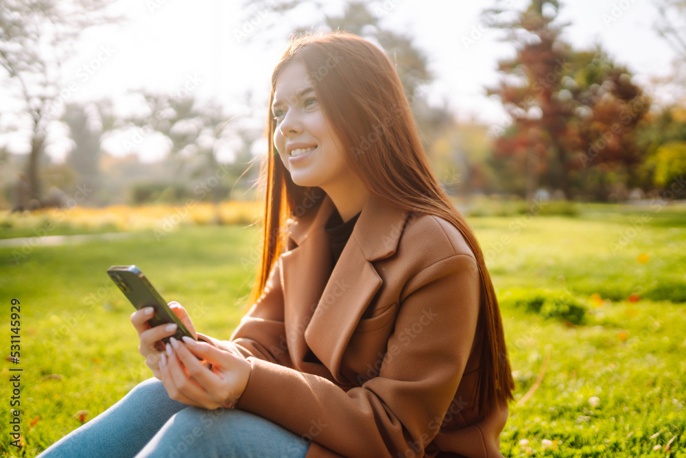 Pretty woman with smartphone having a good time in autumn weekend. People, lifestyle, relaxation and vacations concept. Pretty woman with smartphone having a good time in autumn weekend. People, lifestyle, relaxation and vacations concept.