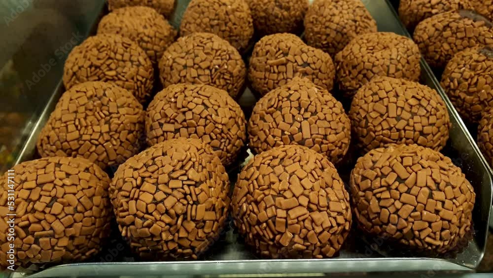Closeup of several Brazilian chocolate fudge ball (brigadeiros) in a Brazilian bakery showcase.