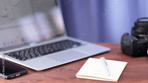 Vlogger workplace. Laptop, smartphone, notebook and camera on a wooden table. Freelancing and video blogging concept