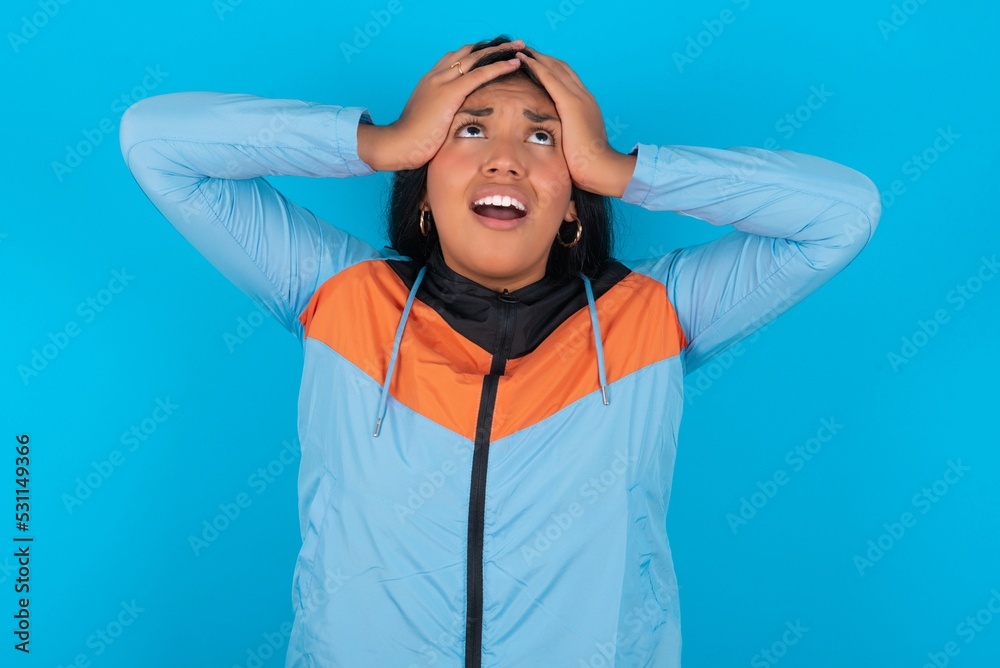 Horrible, stress, shock. Portrait emotional crazy young beautiful latin woman wearing sportswear clasping head in hands. Emotions, facial expression concept. Horrible, stress, shock. Portrait emotional crazy young beautiful latin woman wearing sportswear clasping head in hands. Emotions, facial expression concept.