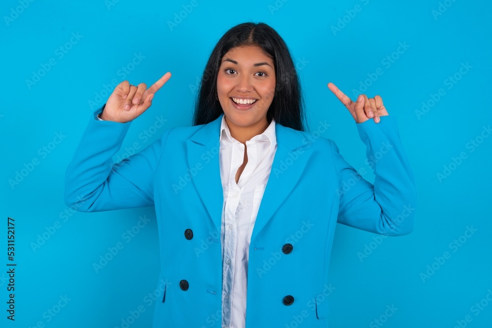 Cheerful Young latin businesswoman wearing blue blazer over blue background demonstrating hairdo