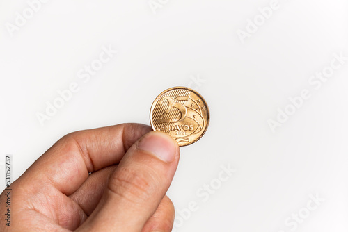 Hand holding Brazilian Real Twenty-Five Centavos coin on white background photo