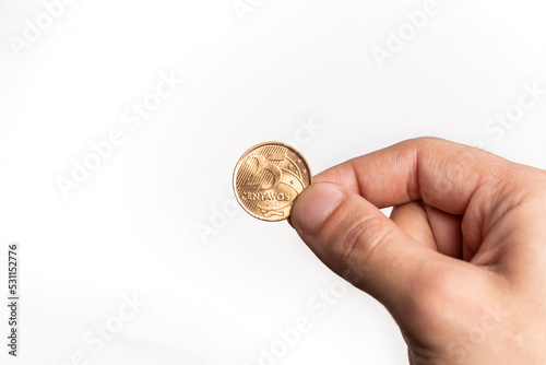 Hand holding Brazilian Real Twenty-Five Centavos coin on white background photo