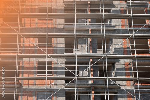 scaffolding of red brick apartment building. View of metal scaffolding in daylight