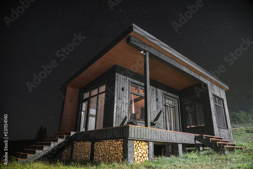 Modern wooden tiny cabin at night with sky full of stars