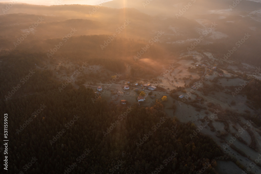 aerial view of morning lights, sun shines over clouds and plateau houses and trees with blue sky and foggy mountains aerial view of morning lights, sun shines over clouds and plateau houses and trees with blue sky and foggy mountains