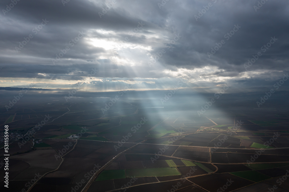 aerial view of light rays, sun beams over the fields on a cloudy day