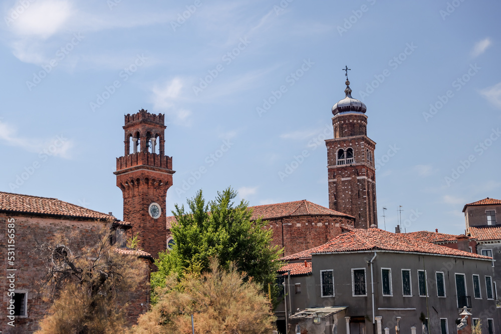 Murano, Italy - July 7, 2022: A bell tower seen through the trees in Murano Italy

