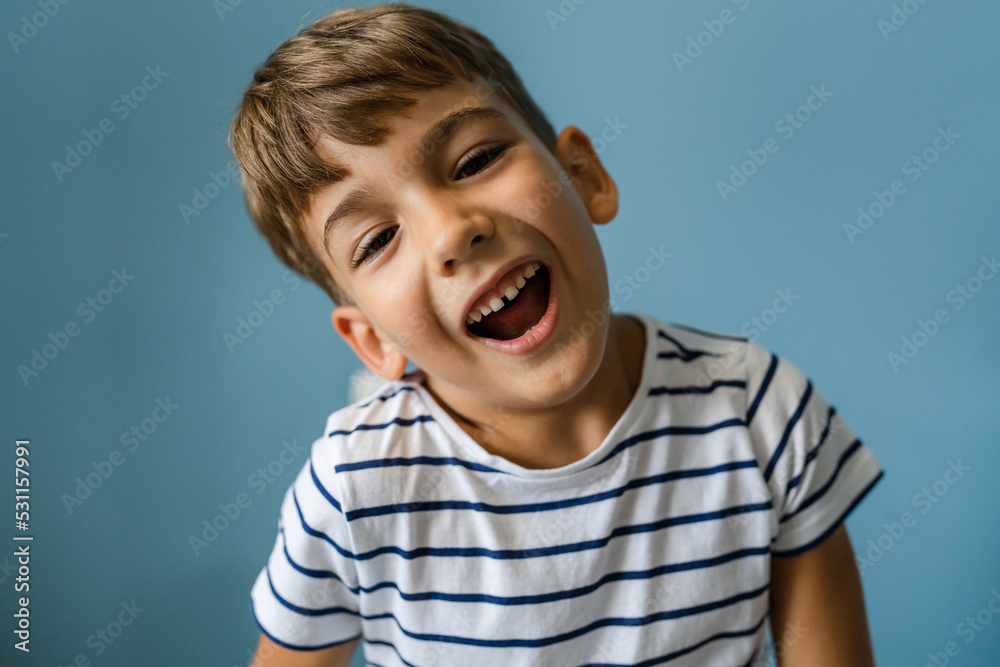 One caucasian boy child in front off blue wall portrait goofing around One caucasian boy child in front off blue wall portrait goofing around
