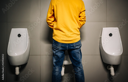 Man peeing to toilet bowl in restroom