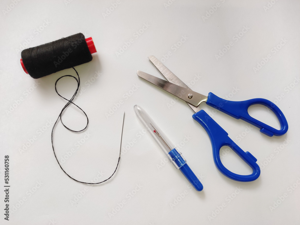 Fabric scissors, seam ripper, black thread, hand sewing needle isolated on a white background. Fabric scissors, seam ripper, black thread, hand sewing needle isolated on a white background.