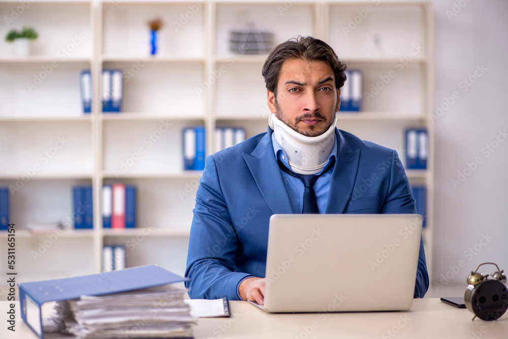 Young male employee after accident sitting at workplace Young male employee after accident sitting at workplace