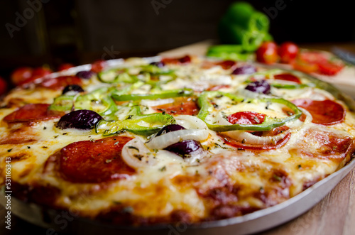 pizza on the table decorated with olive oil, tomatoes and chives and peppers