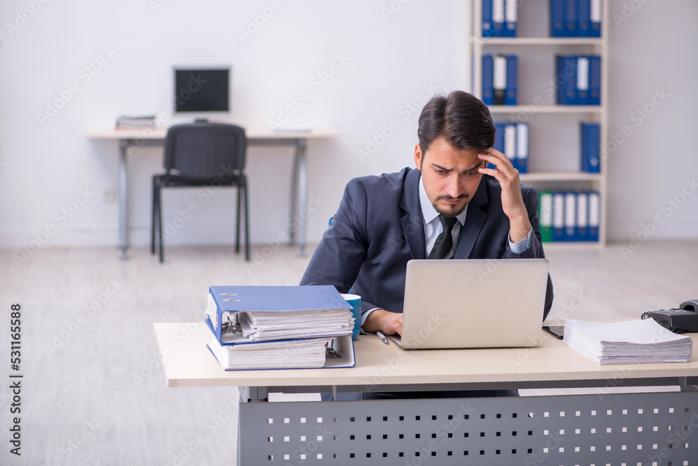 Young male employee sitting at workplace Young male employee sitting at workplace