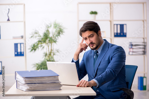 Young male employee and too much work in the office